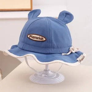 Détail chapeau soleil bébé avec oreilles d'ours et patch Planwich en bleu denim