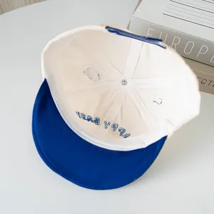 Detail of baby baseball cap interior showing blue brim and adjustable strap buckle