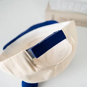 Detail of adjustable velcro strap on cream and royal blue baby baseball cap with bear motif