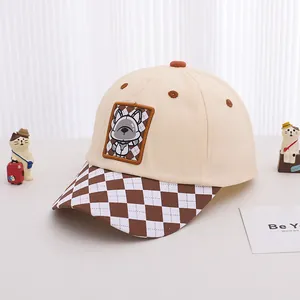 Detail of beige and brown checkered visor and cartoon dog patch on cotton baseball cap