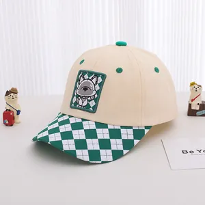 Close-up of children baseball cap with cartoon patch and green checkered pattern brim