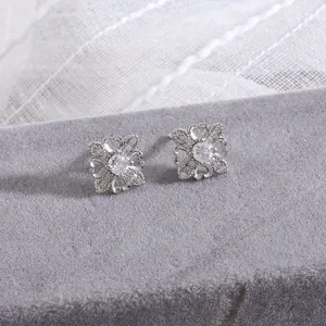 Macro shot of silver four-leaf clover earrings with micro-set zircons on lace