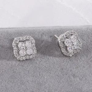 Macro shot of silver clover earrings with micro-pave zircons on a grey velvet stand