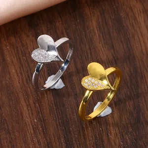 Detail of copper micro-set zircon heart rings in gold and silver finish on wood