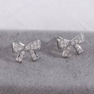 Detailed view of silver bow earrings with zircon micro-pave on a velvet display