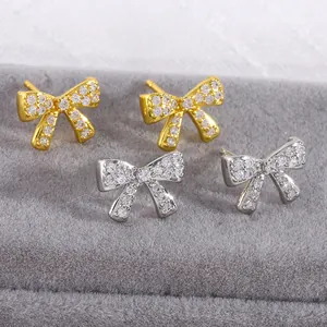 Sparkling micro-pave zircon bow earrings in gold and silver finish on velvet display