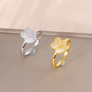 Luxe gouden en zilveren dubbele hartringen met zirkonia op een leren achtergrond