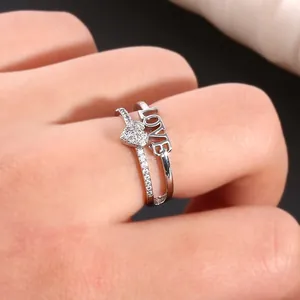 Macro detail of silver double-layer ring with micro-pave heart and LOVE hollow design