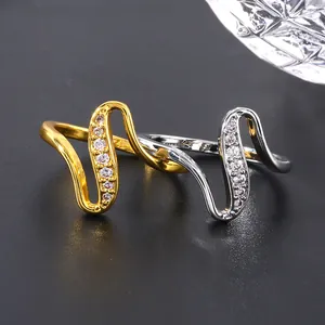 Polished gold and silver wave rings with micro-paved cubic zirconia on a gray background