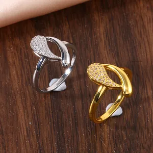 Macro detail of gold and silver teardrop rings with zircon micro-pave on wood surface