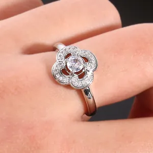Macro shot of silver four-leaf clover ring with sparkling zircon stones on female hand