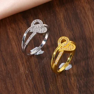 Détail de bagues cœur en argent et or avec zircons micro-pavés sur bois foncé