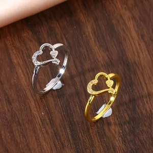 Dettaglio di anelli a doppio cuore in oro e argento con zirconi incastonati brillanti