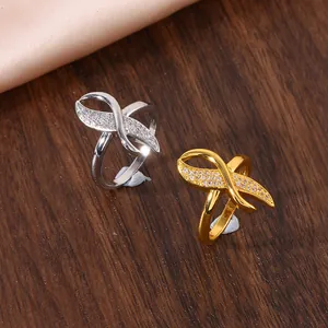 Detailed view of silver and gold infinity rings with micro-set zircon on wood background