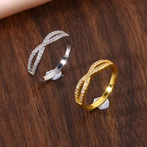 Close-up of infinity cross rings in gold and silver with shimmering micro-pave stones
