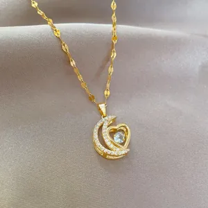 Detalle de colgante de luna y corazón dorado con circonitas cúbicas microengastadas