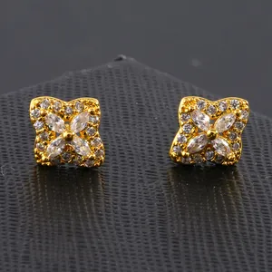 Détail macro de boucles d'oreilles trèfle doré avec zircons sur cuir noir