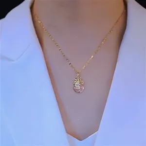 Close-up of a gold money bag pendant necklace with zircon inlay and pink gemstone detail