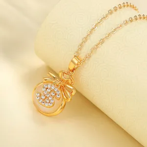 Macro view of gold lucky money bag pendant necklace with cubic zirconia and bow detail