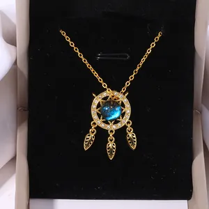Elegant gold dreamcatcher necklace with blue starry orb and crystal feathers on velvet