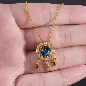 Macro detail of dreamcatcher pendant with blue galaxy stone and hanging golden leaves