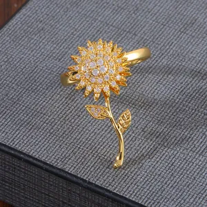 Anillo giratorio de girasol dorado con circonitas sobre fondo de tela gris elegante