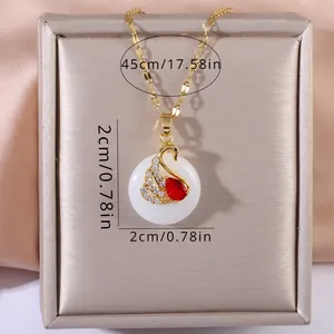 Macro detail of swan pendant necklace with white cabochon and pavé crystals on gold chain