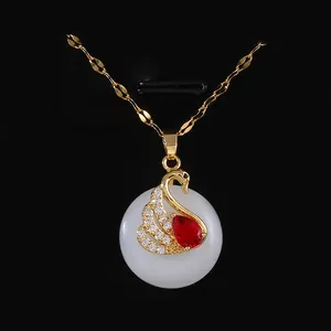 Elegant gold swan necklace with red gemstone and white jade pendant on black background