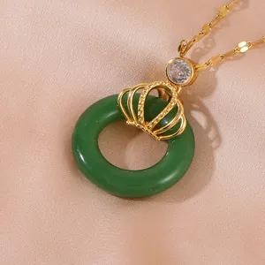 Luxurious crown pendant necklace with dark green ring and glittering zircon on silk backdrop