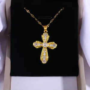 Luxurious gold cross pendant necklace with micro-paved cubic zirconia on a jewelry box