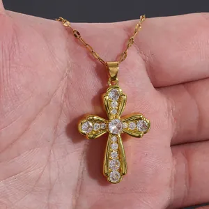 Close-up of a gold cross pendant necklace featuring micro-pave cubic zirconia on hand
