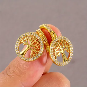 Golden Tree of Life earrings with cubic zirconia inlay shown for scale by hand