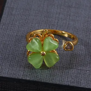 Draaibare gouden klaverring met groene kattenoogstenen en een hartvormig zirkonia accent