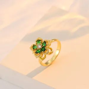 Détail d'une bague fleur rotative dorée avec pierres vertes et bords perlés vintage