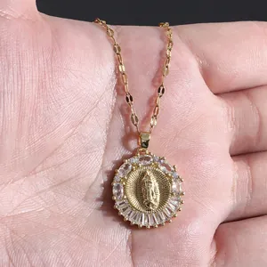 Macro view of gold-plated Virgin Mary pendant necklace held in hand to show scale