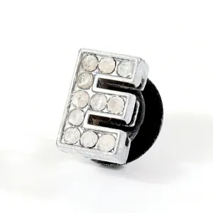 Macro shot of silver letter E shoe charm with sparkling rhinestones and black back clasp
