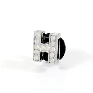 Detailed macro view of silver H letter charm with sparkling rhinestones for shoes