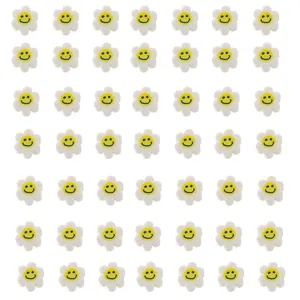 Vue macro de perles fleurs en pâte polymère blanche avec centre smiley jaune en grille