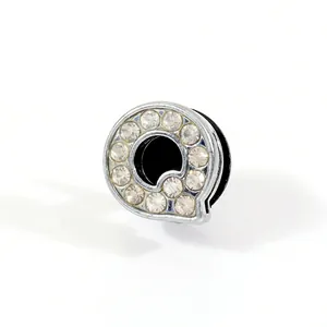 Close-up of letter Q shoe charm accessory with sparkling rhinestones and silver plating