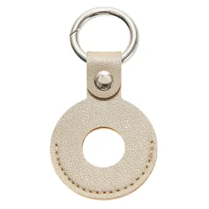 Detailopname van champagne goud lederen AirTag houder met metalen ringetje