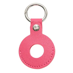 Detail van rozerode lederen AirTag-hoes met zilveren veerring en lychee-textuur