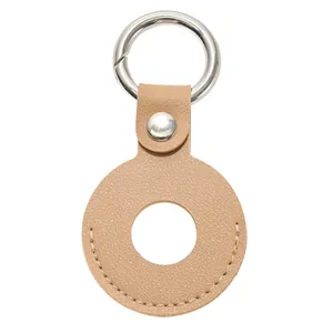 Detail van bruine lederen AirTag-hoes met korrelstructuur en zilveren veerring
