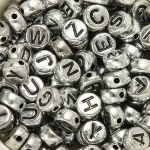 Dettaglio macro di perline dell'alfabeto in argento vintage con lettere incise e fori