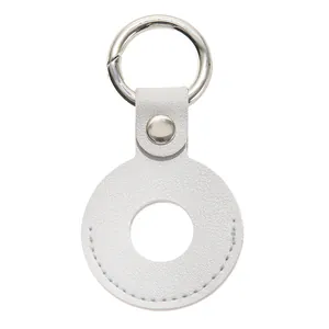 Detail van witte AirTag-hoes van lychee-leer met zilveren metalen veerring gesp