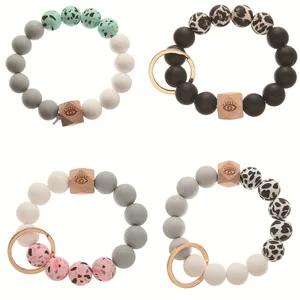 Detail of silicone beaded keychains with leopard print, cow pattern, and eye-engraved wood bead