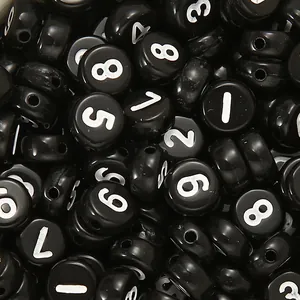 Vista macro di perle tonde in acrilico nero con numeri bianchi per creazione di gioielli