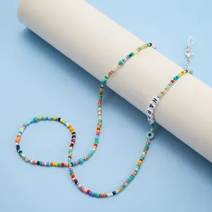 Dettaglio di perline colorate, ciondolo 'HAPPY' e occhio di bue per laccio occhiali
