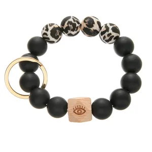 Detail of silicone beaded keychain bracelet with leopard print and engraved evil eye wood bead