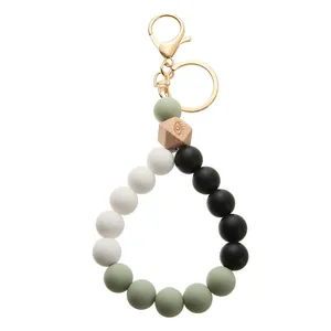 Detail of silicone beaded keychain featuring a carved wood bead and golden lobster clasp