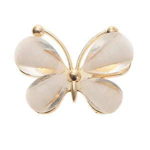 Close-up of a butterfly shoe charm with gold metal frame and colorful glitter inlay
